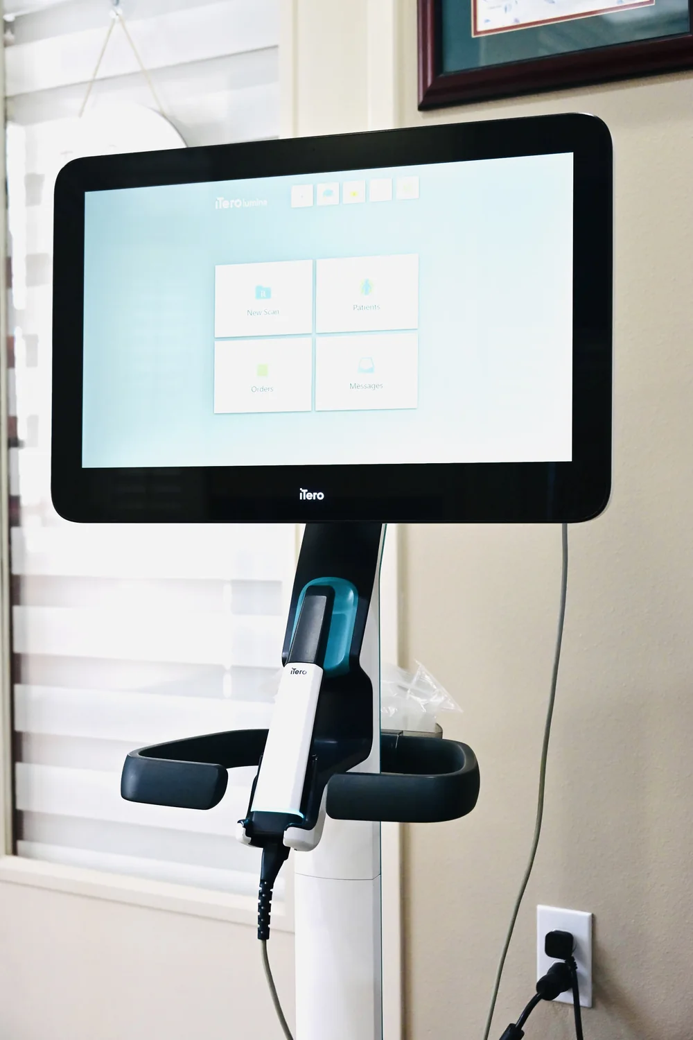 The iTero intraoral scanner, a small wand on a stand, used instead of impression trays