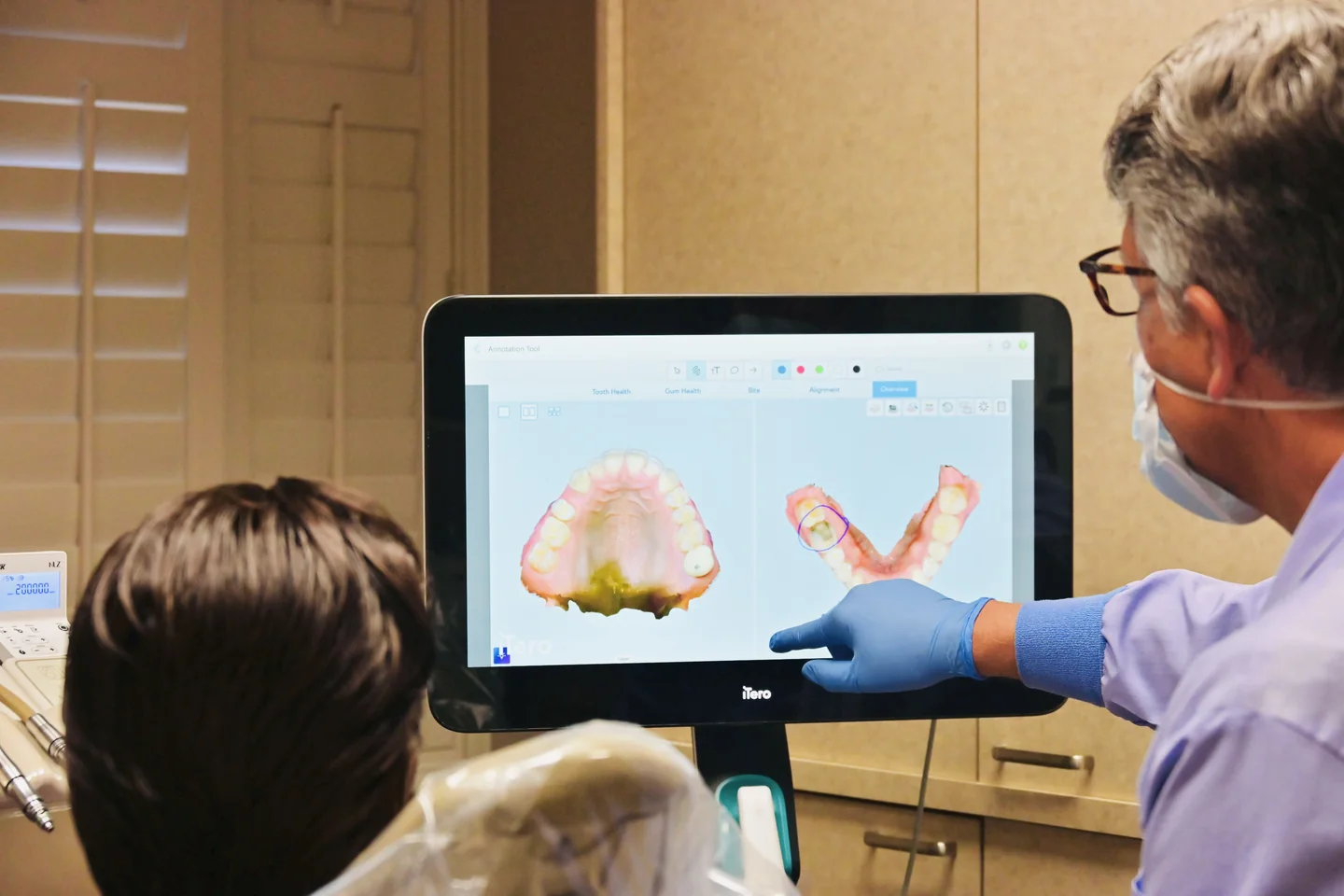 A 3D scan of upper and lower arches on the screen, with Dr. Sandquist pointing at a tooth