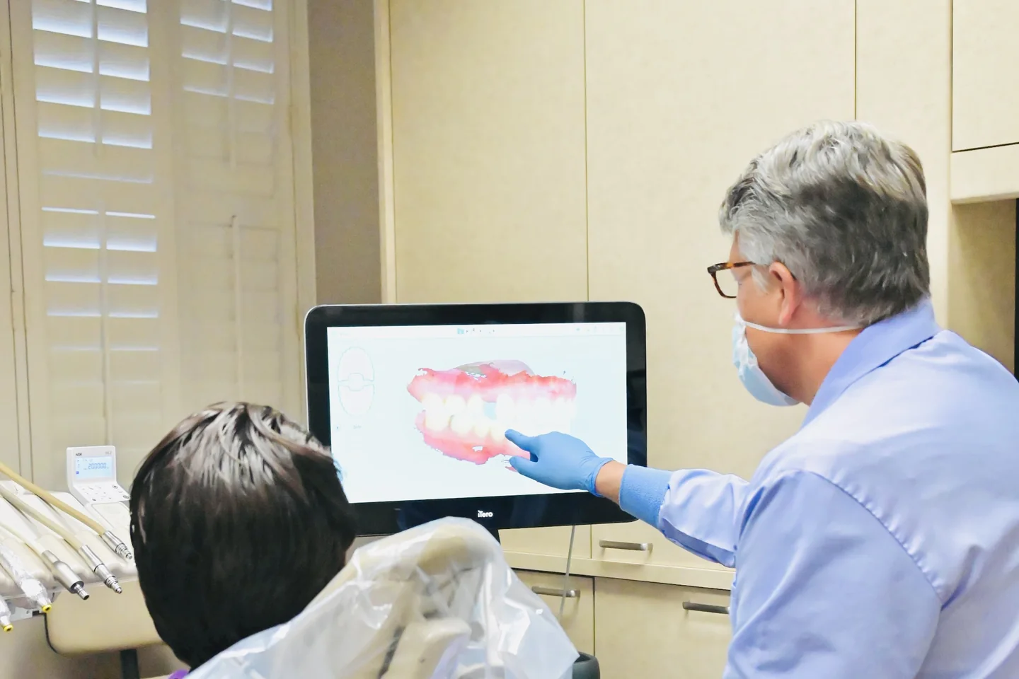 Dr. Sandquist showing a patient their 3D scan on the screen beside the chair